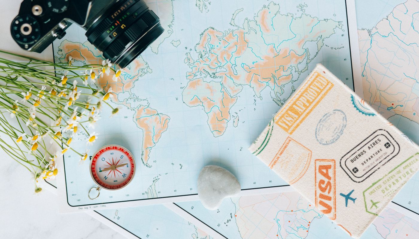 Flat lay of a world map, compass and visa stamps for trip planning